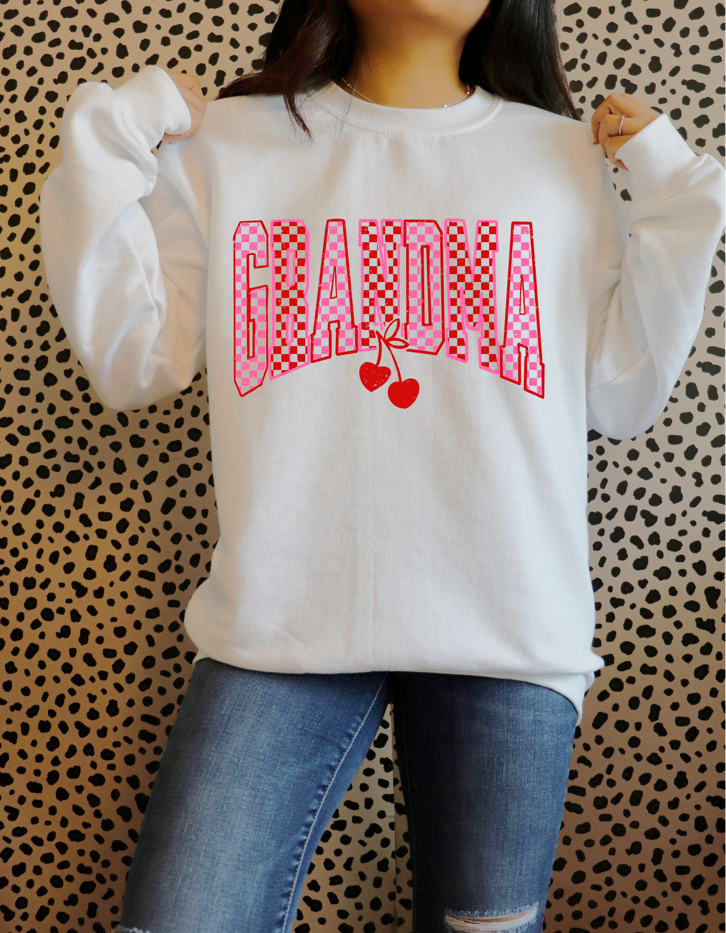Person wearing a white sweatshirt with 'GRANDMA' in red text on a patterned background